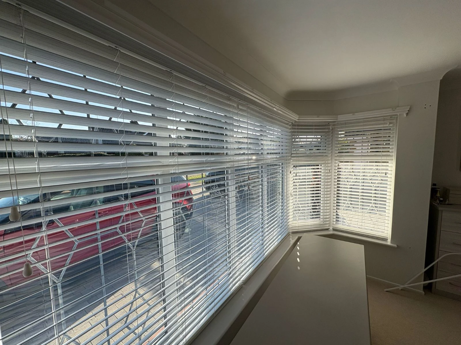 White Faux Wood Venetian Blinds installed in a bay window, providing adjustable light control and privacy in a modern Essex home.