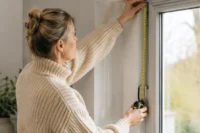 Surveyor measuring a window for made-to-measure blinds before manufacturing and installation.