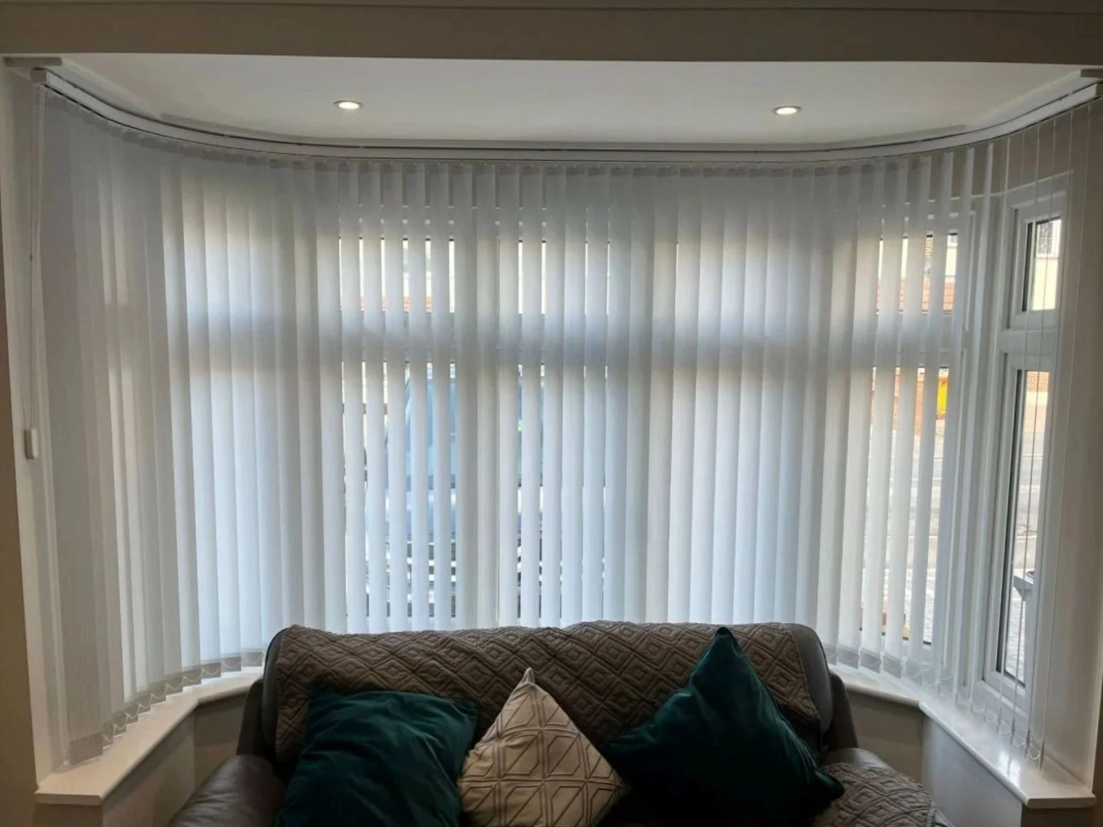 White vertical blinds installed within a splay bay window in an Essex home, offering adjustable privacy and light control across angled window sections.