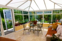 Bright conservatory with a glazed roof and large windows on a sunny summer day.
