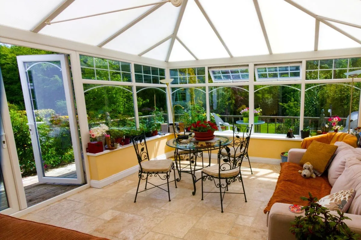 Bright conservatory with a glazed roof and large windows on a sunny summer day.