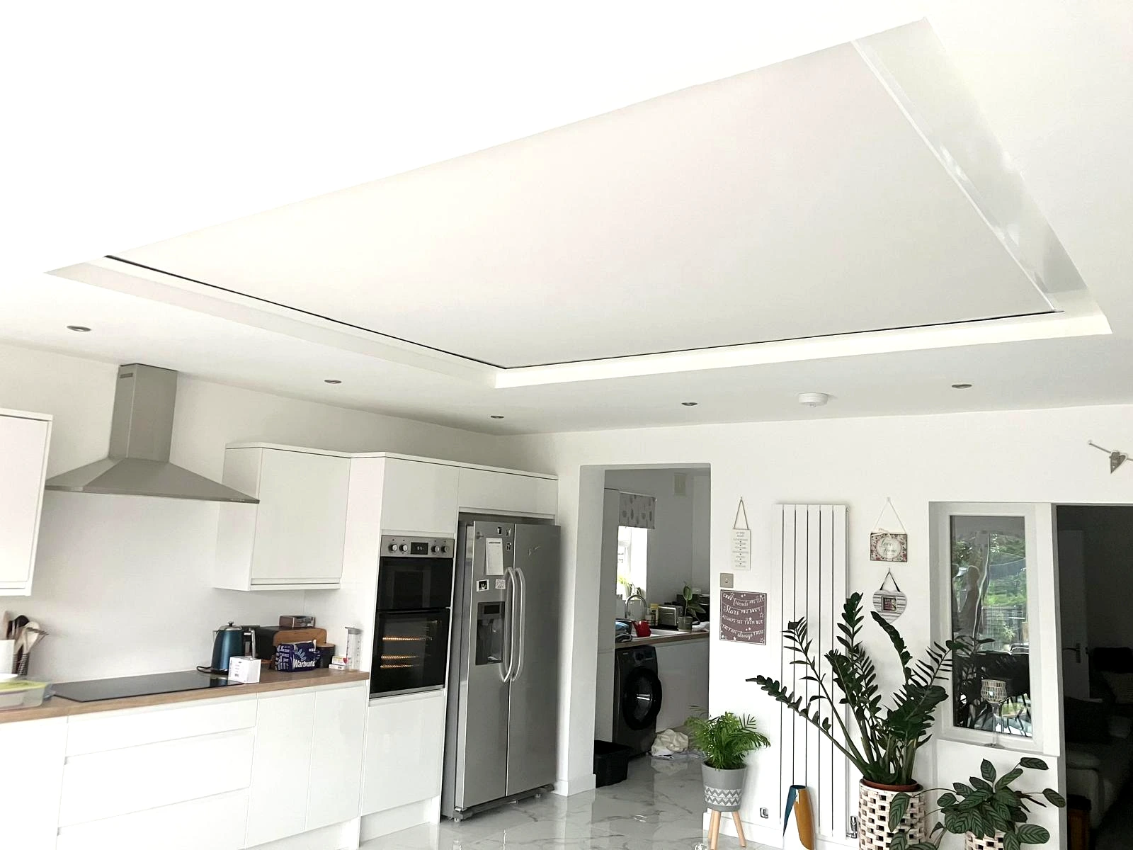 Modern kitchen extension with a white rooflight blind fully closed across a large roof lantern to reduce sunlight and glare.