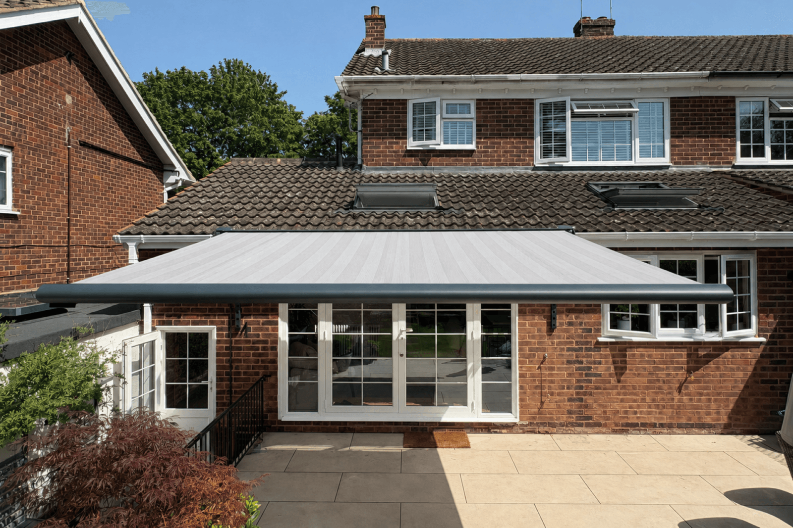 Grey patio awning extended over the rear terrace of an Essex home.