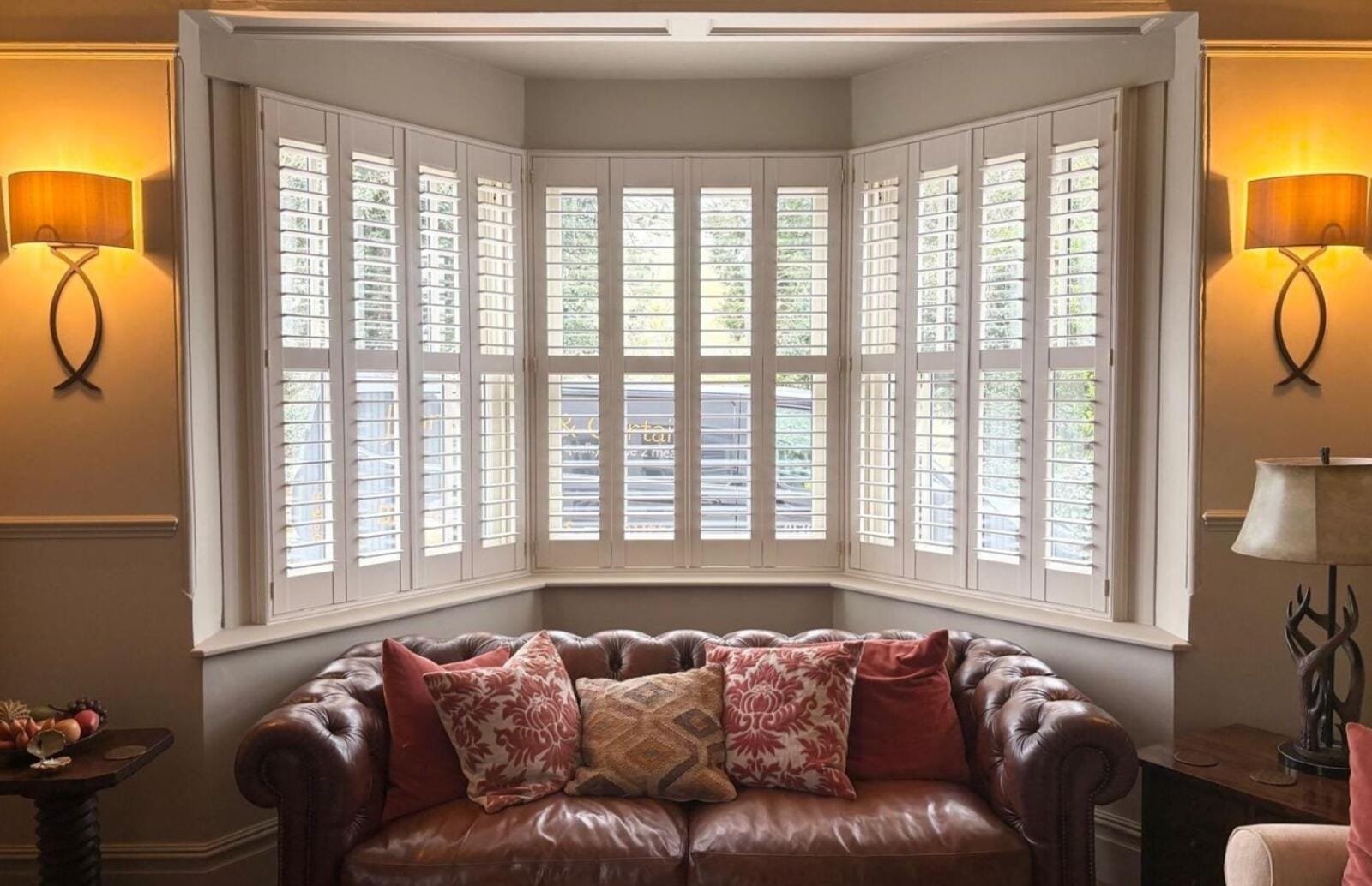 Full-height white plantation shutters fitted to a bay window in an Essex living room.