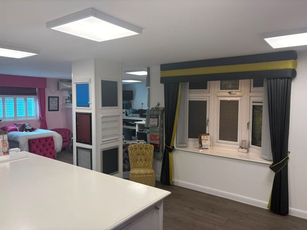 Grey and green made-to-measure curtains and pelmet with pleated blind displays inside John’s Blinds & Curtains’ Wickford showroom.